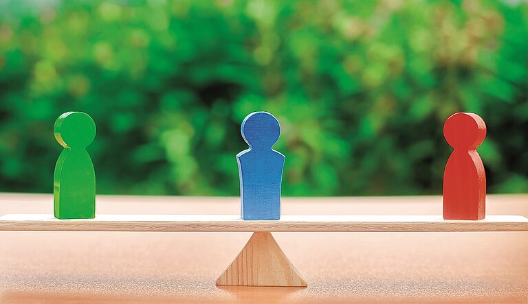 Drei Figuren auf einem Holzbalken